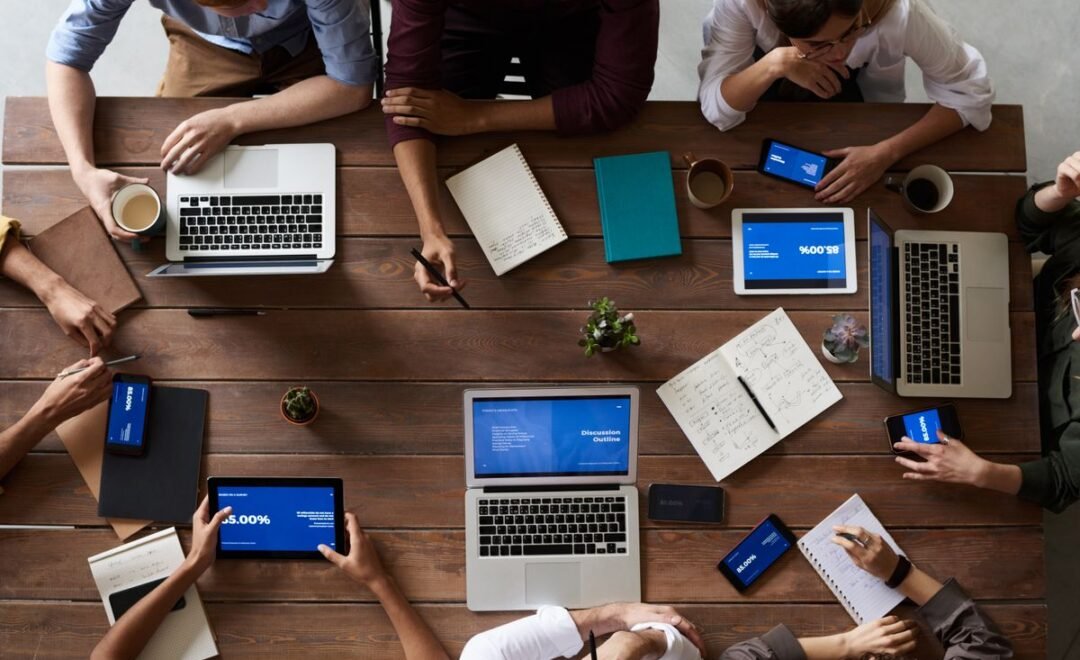 Team collaborating around a table of laptops and devices