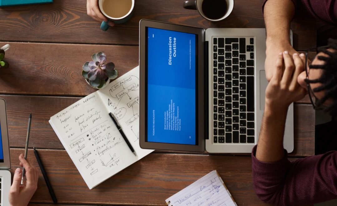 A laptop and handwritten scoping notes on a table