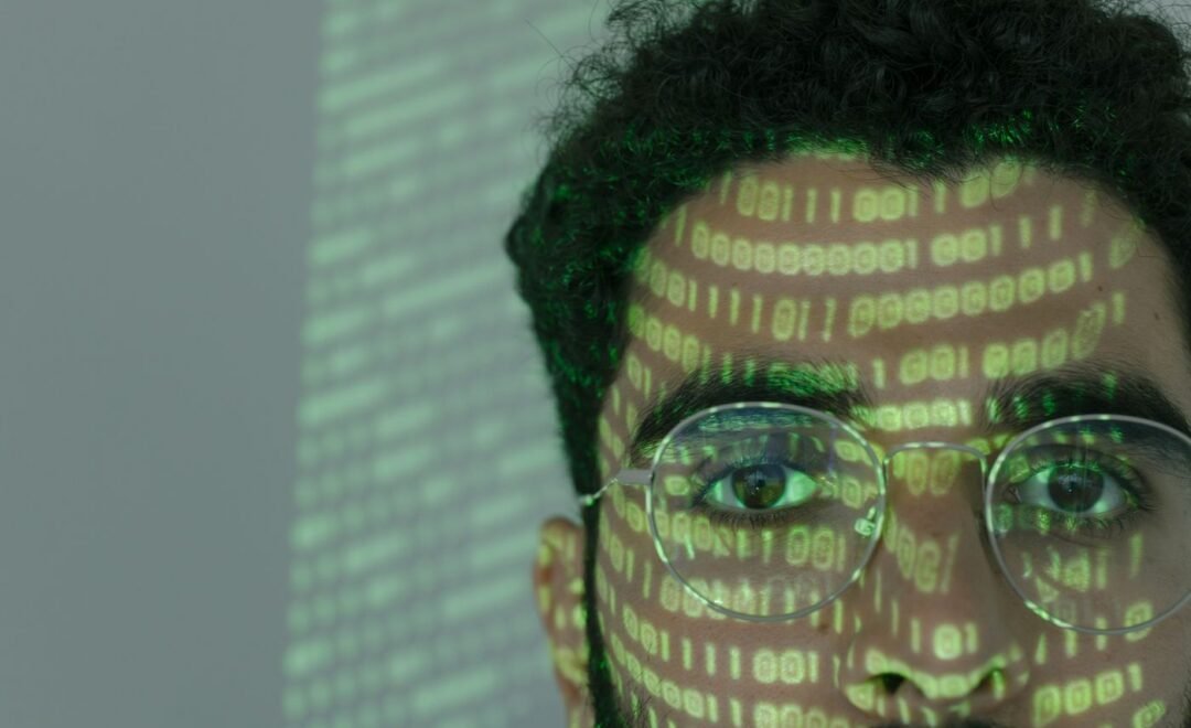 A person in front of a screen of scrolling code